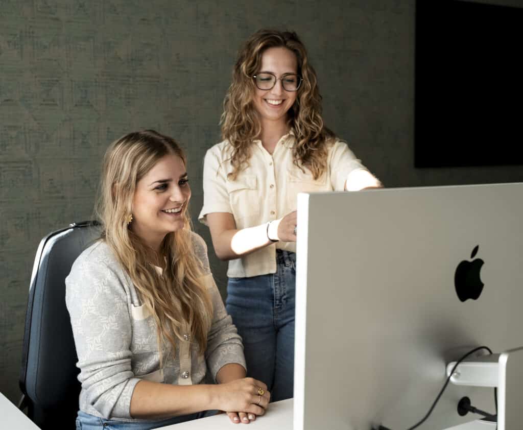 Collega's werken samen en kijken naar computer.