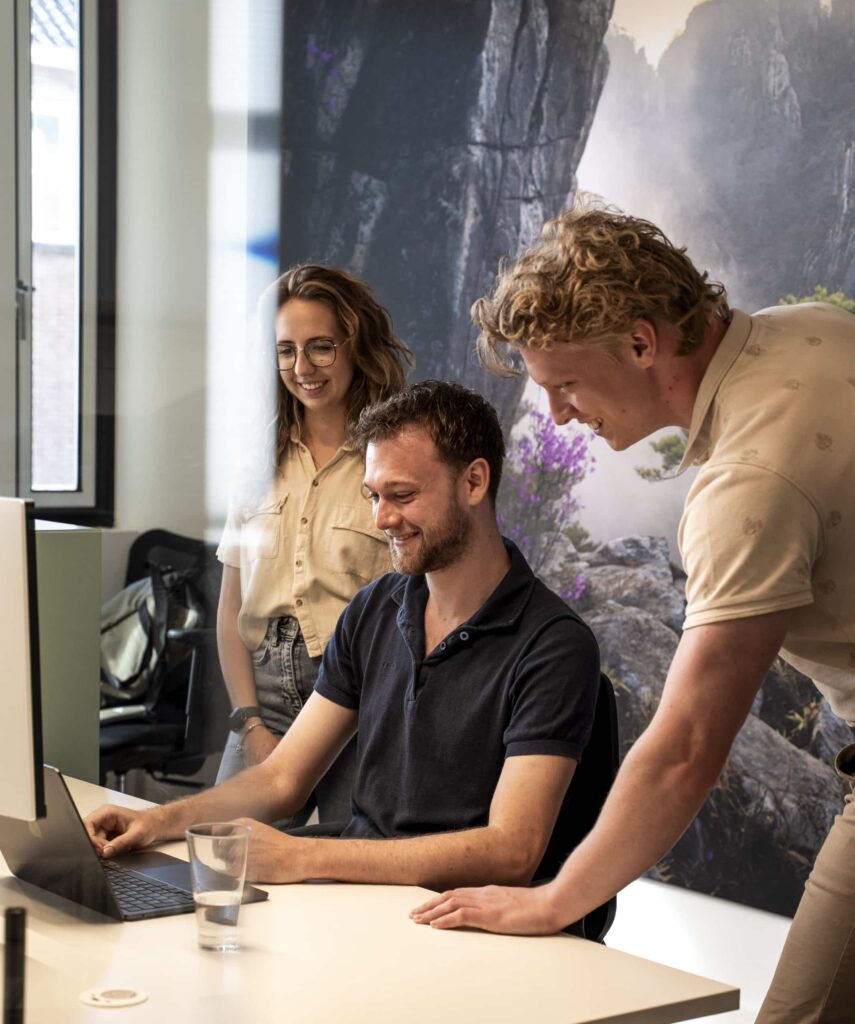 Drie collega's in overleg achter laptop