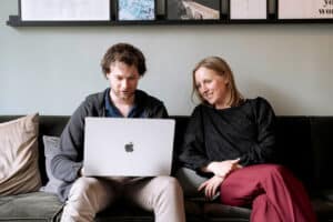 Man even vrouw samen op een bank met laptop tijdens een re-integratietraject.